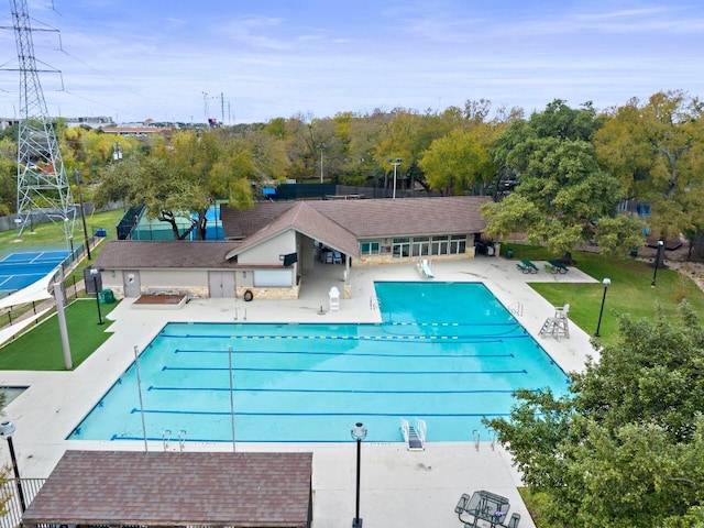 community pool with a lawn, a patio area, and fence
