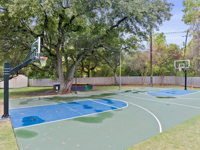 view of basketball court with fence and basketball hoop