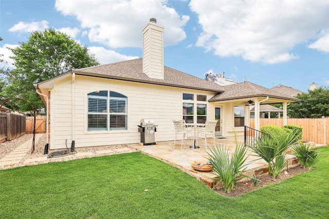 back of property with a yard, a chimney, a fenced backyard, and a patio area