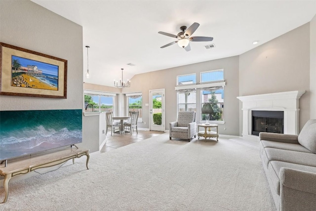 living room featuring visible vents, baseboards, carpet floors, a fireplace with raised hearth, and ceiling fan with notable chandelier