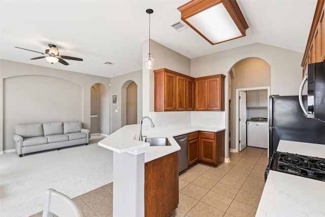 kitchen with arched walkways, a peninsula, open floor plan, and stainless steel appliances