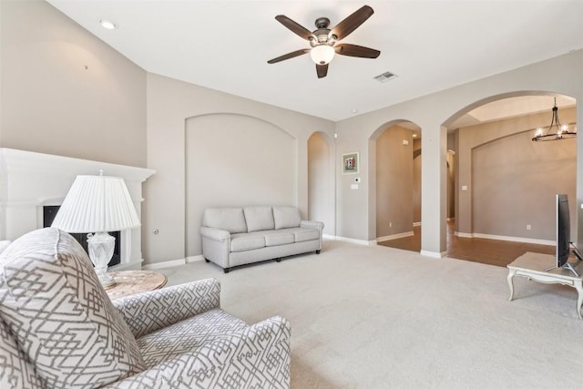 living room with carpet floors, arched walkways, and visible vents