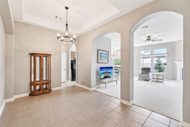 spare room featuring visible vents, arched walkways, ceiling fan with notable chandelier, and light tile patterned flooring