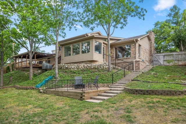 back of property with fence, stairs, a chimney, a lawn, and a patio