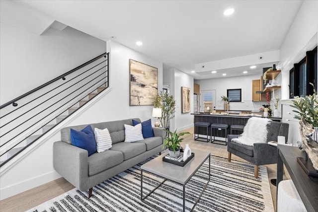 living area with recessed lighting, stairs, light wood-style floors, and baseboards