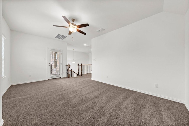 empty room featuring visible vents, a ceiling fan, and dark carpet