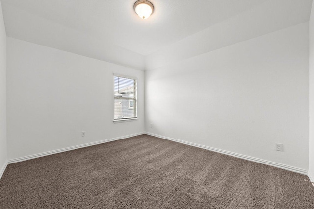 unfurnished room with baseboards and dark colored carpet