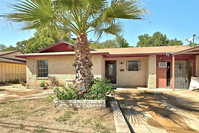 ranch-style house with brick siding and an AC wall unit