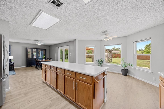 4325 Dos Cabezas Dr, Austin, TX 78749 - kitchen featuring ceiling fan, light wood-style floors, a textured ceiling, light countertops, and a center island