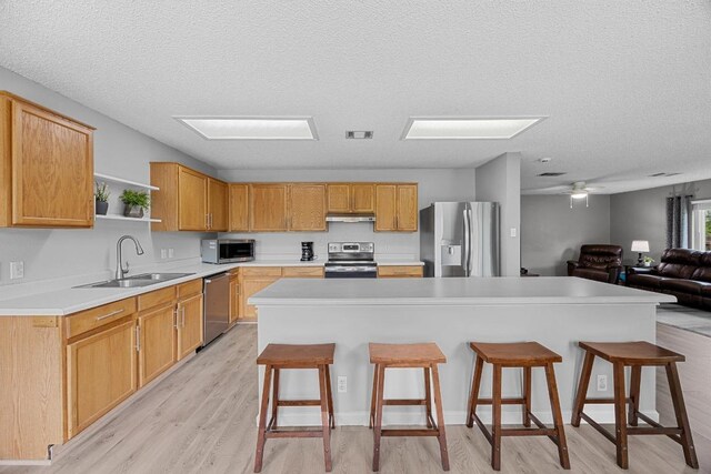 4325 Dos Cabezas Dr, Austin, TX 78749 - kitchen with appliances with stainless steel finishes, a sink, under cabinet range hood, open shelves, and light wood-type flooring