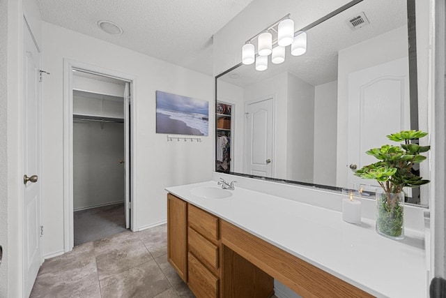 4325 Dos Cabezas Dr, Austin, TX 78749 - bathroom with vanity, a spacious closet, a textured ceiling, and baseboards