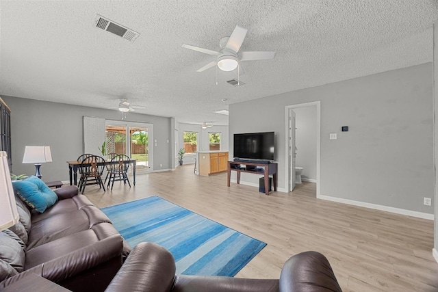 4325 Dos Cabezas Dr, Austin, TX 78749 - living room with a ceiling fan, a textured ceiling, light wood finished floors, and baseboards