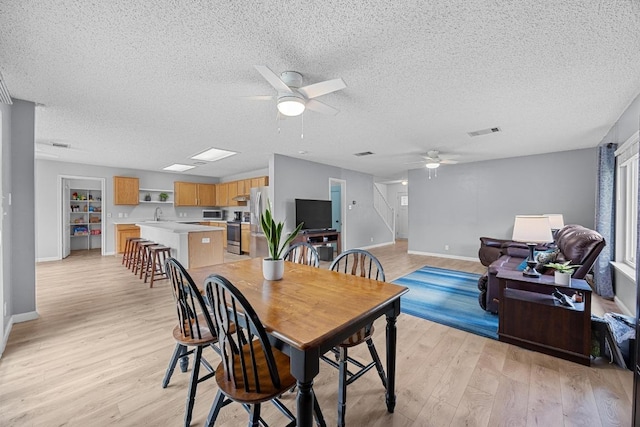 4325 Dos Cabezas Dr, Austin, TX 78749 - dining room featuring a ceiling fan, light wood finished floors, a textured ceiling, baseboards, and stairway