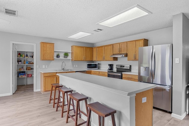 4325 Dos Cabezas Dr, Austin, TX 78749 - kitchen with stainless steel appliances, a textured ceiling, under cabinet range hood, open shelves, and light wood-style flooring
