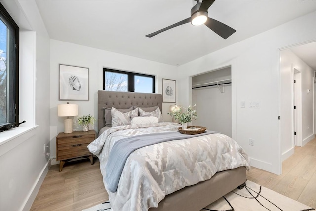 bedroom with light wood-style floors, baseboards, ceiling fan, and a closet
