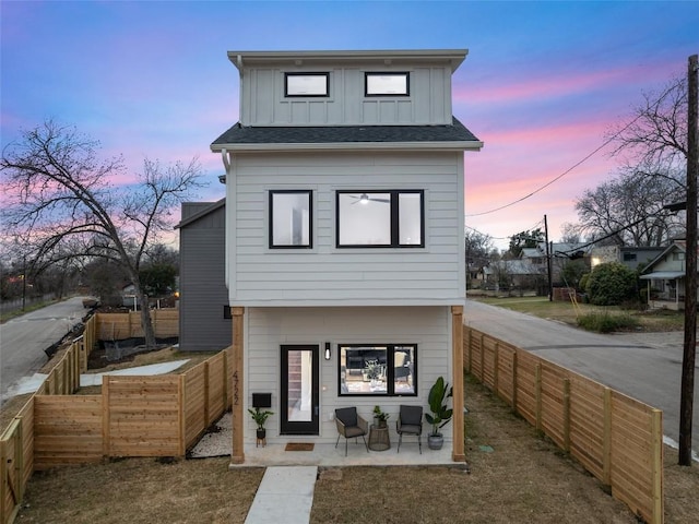 back of house featuring board and batten siding, a fenced backyard, and a patio area