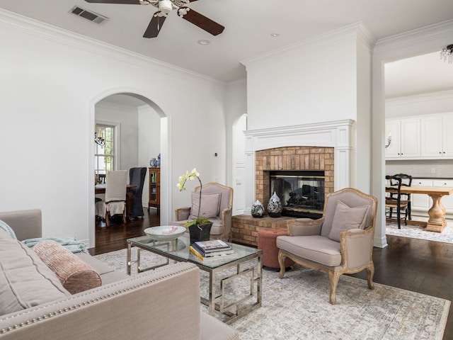 living area with visible vents, arched walkways, a ceiling fan, and wood finished floors