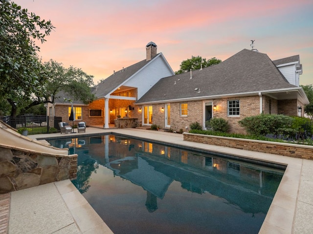 view of swimming pool featuring fence, a water slide, a patio area, and a fenced in pool