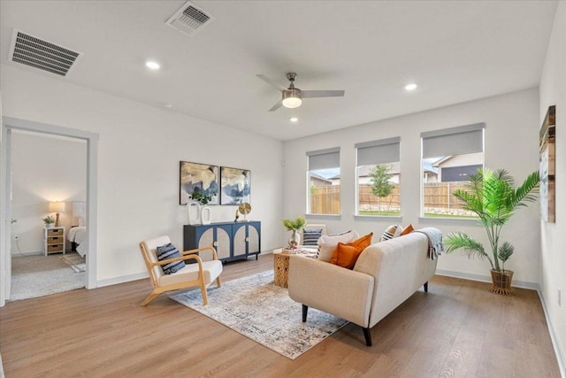 living area with a ceiling fan, light wood-type flooring, and visible vents