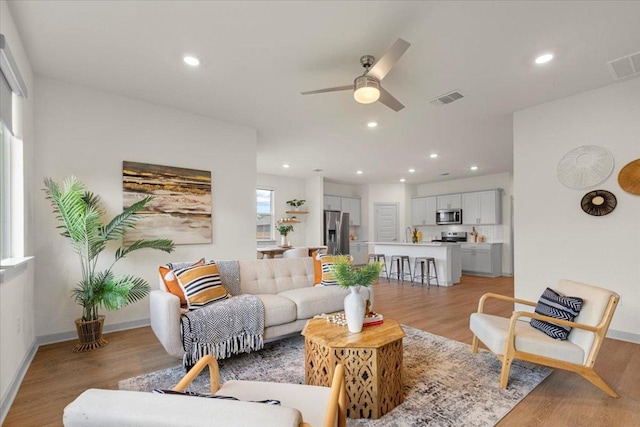 living area featuring ceiling fan, visible vents, and light wood-style flooring