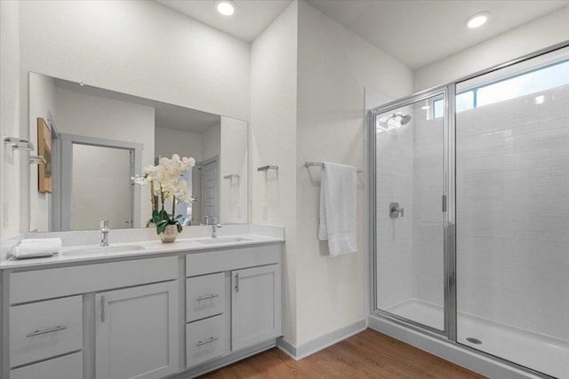 full bath with baseboards, a sink, wood finished floors, and a shower stall