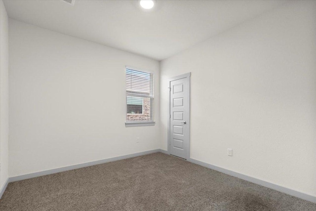 spare room featuring carpet flooring and baseboards