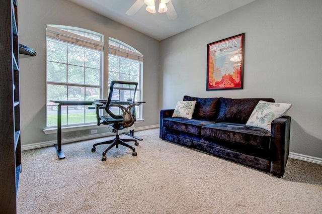 carpeted office space featuring baseboards and ceiling fan
