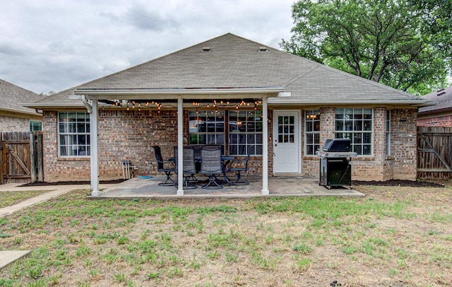 rear view of property featuring a patio, a fenced backyard, a gate, and brick siding