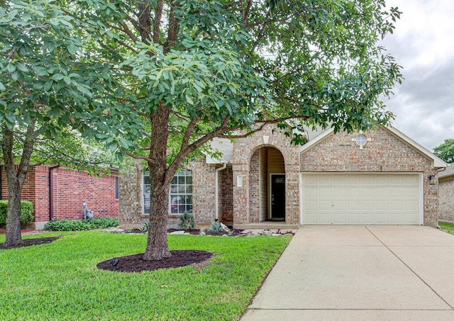 view of front of home with an attached garage, concrete driveway, brick siding, and a front yard