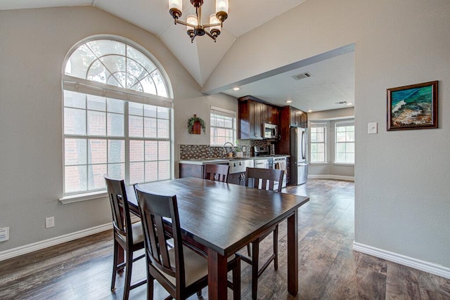 dining space with a chandelier, baseboards, vaulted ceiling, dark wood-type flooring, and visible vents