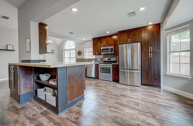 kitchen featuring appliances with stainless steel finishes, open shelves, light wood-style flooring, and visible vents