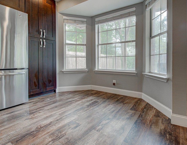 kitchen with light wood-style floors, freestanding refrigerator, baseboards, and dark brown cabinetry