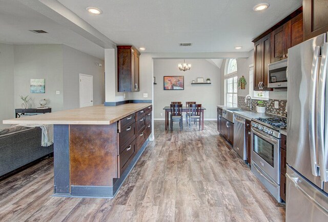 4807 Rutherglen Dr, Austin, TX 78749 - kitchen with appliances with stainless steel finishes, a chandelier, light wood finished floors, a sink, and dark brown cabinetry