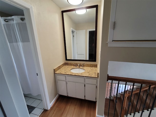 full bath with vanity, baseboards, wood finished floors, and a shower