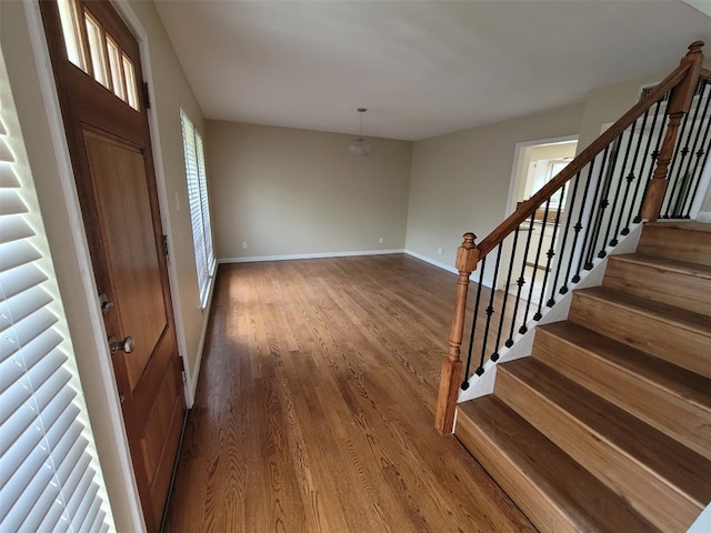 foyer featuring baseboards, stairs, and wood finished floors