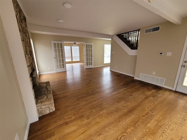 unfurnished living room with visible vents, a ceiling fan, baseboards, and wood finished floors