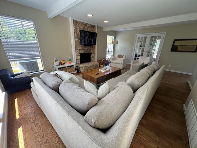 living room featuring wood finished floors, beam ceiling, a fireplace, baseboards, and cooling unit