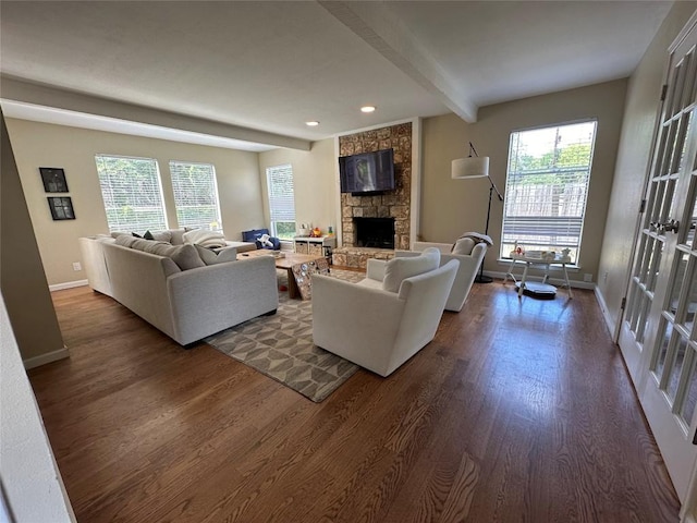 living room featuring baseboards, a stone fireplace, dark wood-style floors, and beam ceiling
