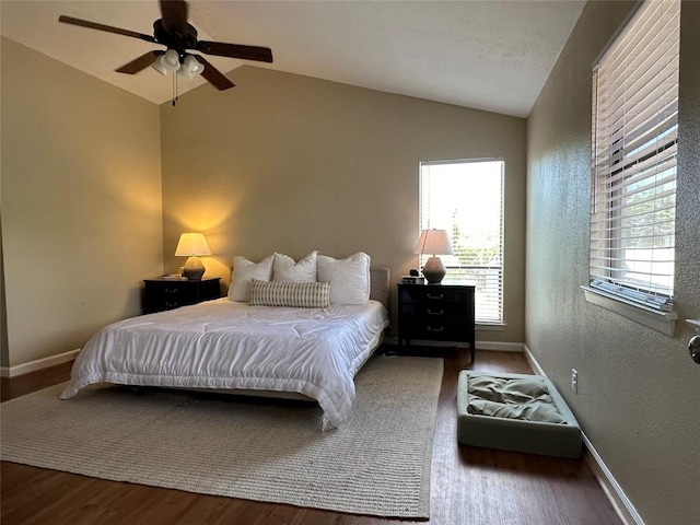 bedroom featuring wood finished floors, baseboards, a textured wall, and lofted ceiling