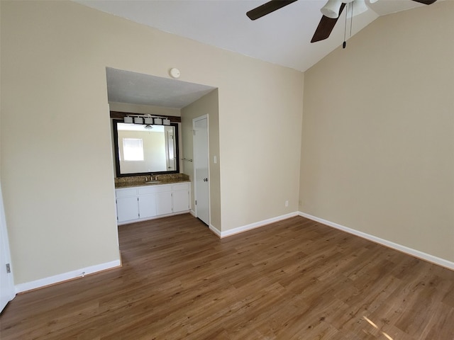 interior space featuring ceiling fan, wood finished floors, a sink, baseboards, and lofted ceiling