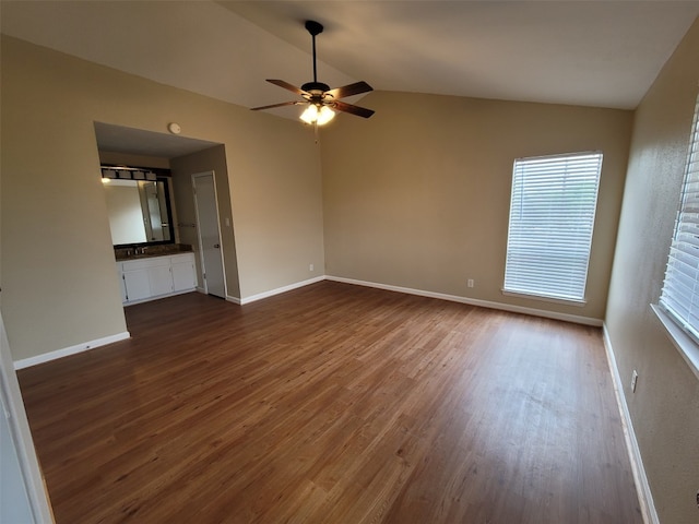 spare room with baseboards, a ceiling fan, dark wood finished floors, and vaulted ceiling
