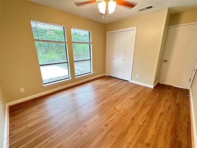 unfurnished bedroom featuring a ceiling fan, visible vents, baseboards, a closet, and light wood-style floors