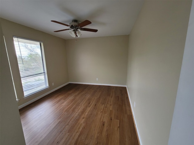 unfurnished room featuring baseboards, ceiling fan, and dark wood-type flooring