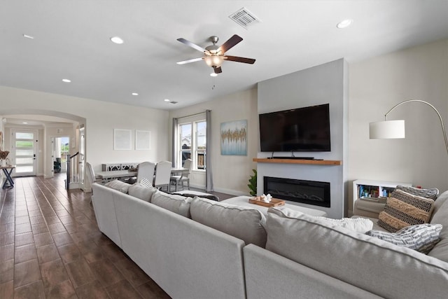 living room with a ceiling fan, visible vents, arched walkways, a glass covered fireplace, and recessed lighting
