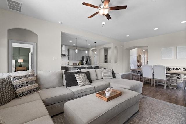 living room with visible vents, ceiling fan, dark wood-type flooring, recessed lighting, and arched walkways