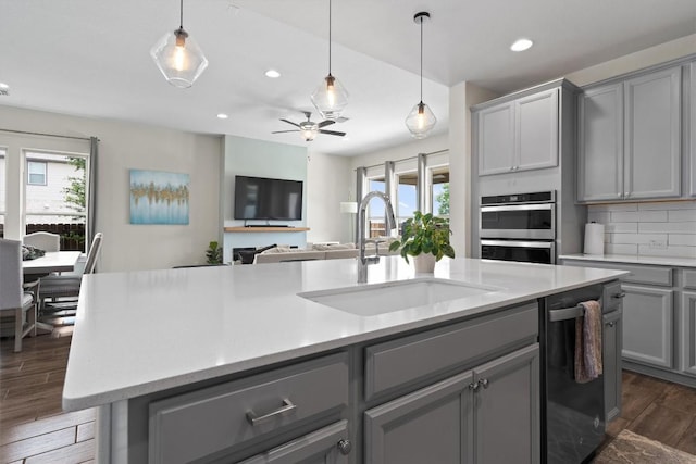 kitchen featuring dark wood-style floors, stainless steel double oven, gray cabinets, light countertops, and a sink