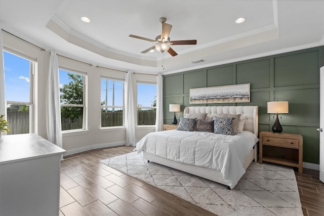 bedroom with visible vents, ornamental molding, a tray ceiling, and multiple windows