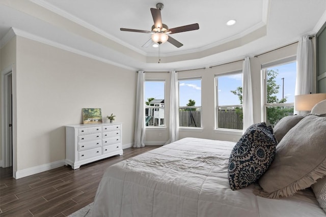 bedroom featuring dark wood finished floors, recessed lighting, baseboards, a tray ceiling, and ornamental molding