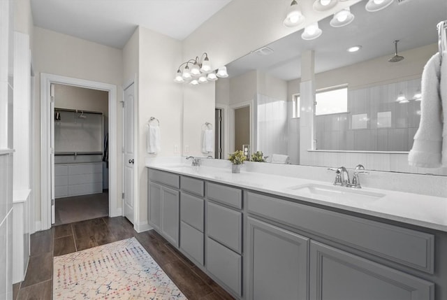 full bathroom featuring double vanity, a sink, and a tile shower