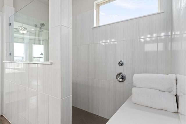 bathroom with a ceiling fan and tiled shower